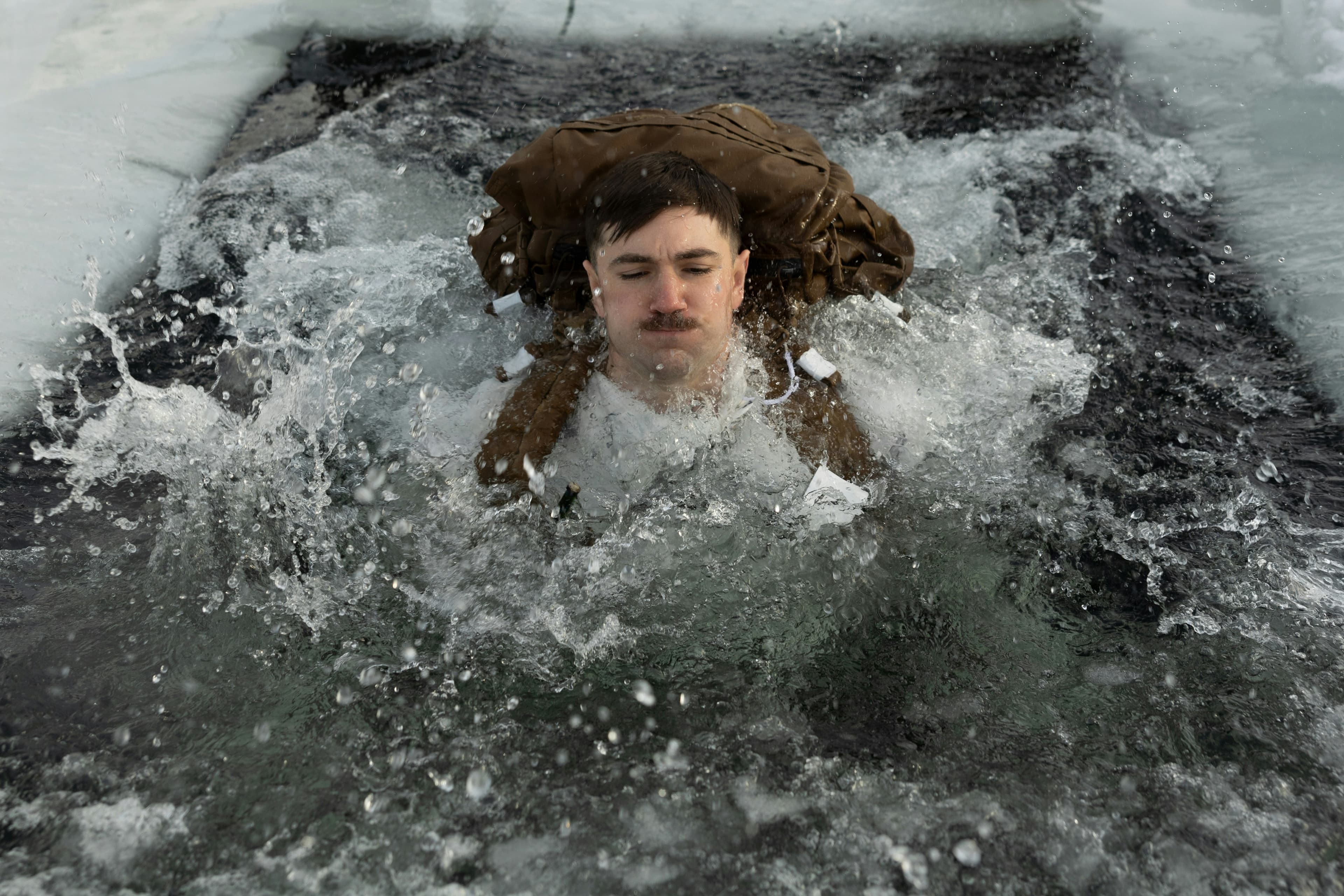 Una persona immersa nell’acqua tra il ghiaccio e gli spruzzi.
